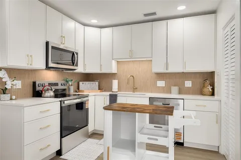 a kitchen with granite countertop white cabinets and stainless steel appliances