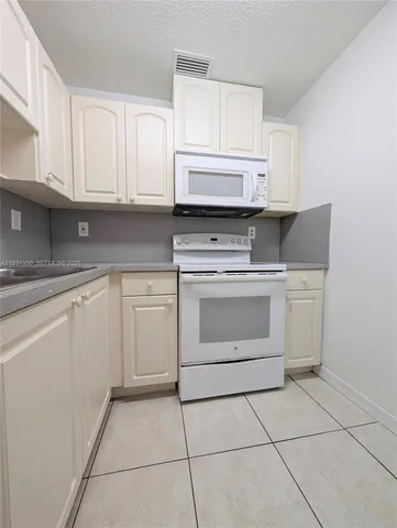 a kitchen with white cabinets and appliances
