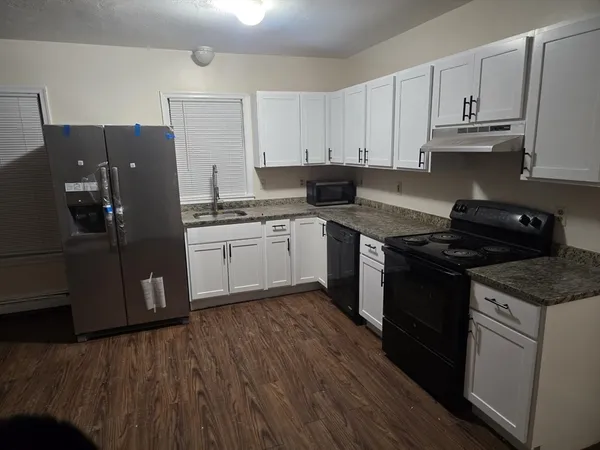 a kitchen with stainless steel appliances granite countertop a stove a refrigerator and a granite counter tops with wooden floors