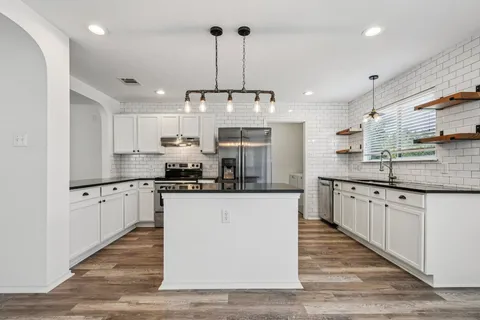 a kitchen with stainless steel appliances granite countertop a sink a stove and a refrigerator