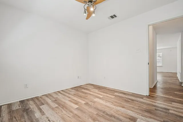 a view of a room with wooden floor and a ceiling fan