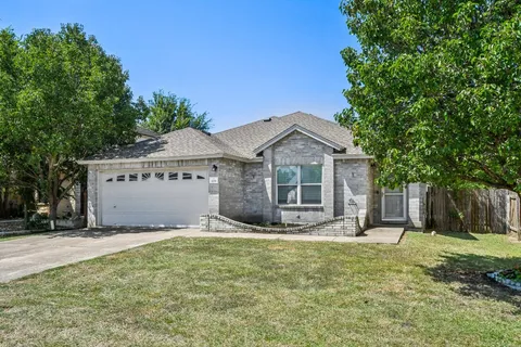 a front view of house with yard and trees in the background