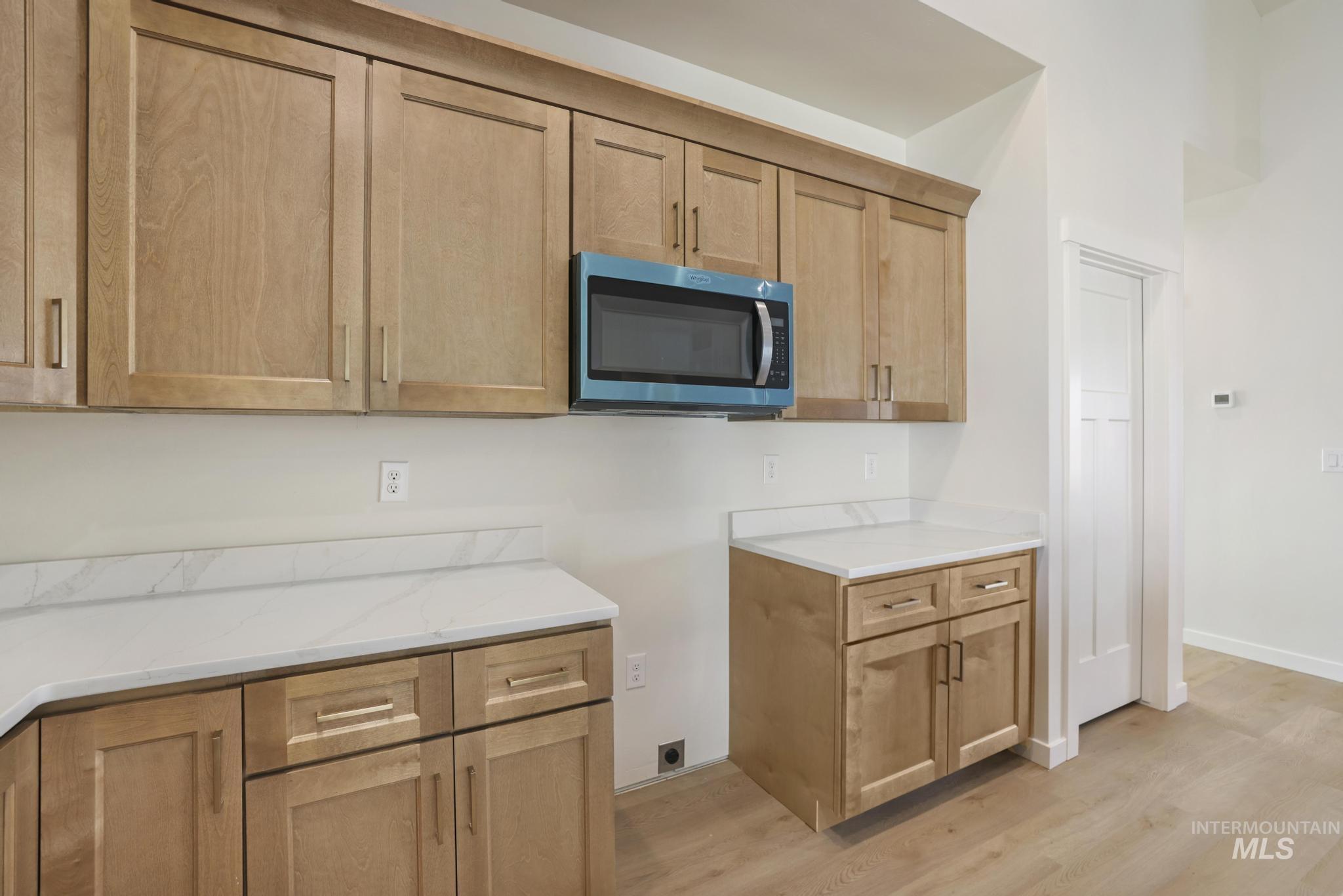 2014 Regan Street Jerome, ID 83338 - Photo 11 of 32 Kitchen featuring stainless steel microwave, light wood-type flooring, light stone counters, and light brown cabinets