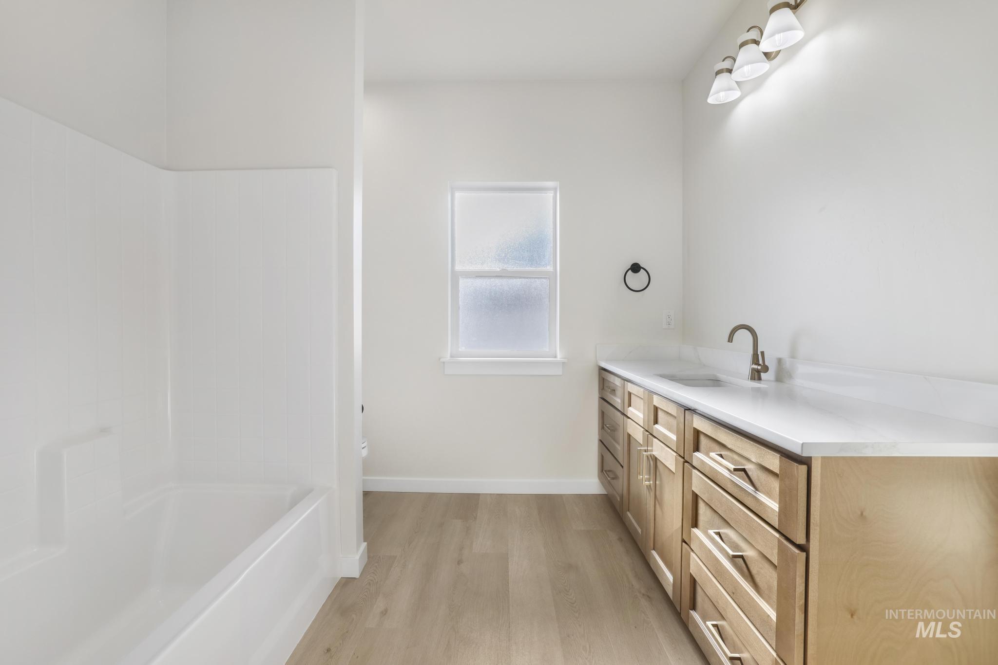 2014 Regan Street Jerome, ID 83338 - Photo 16 of 32 Bathroom featuring vanity, light wood-type flooring, and bathing tub / shower combination