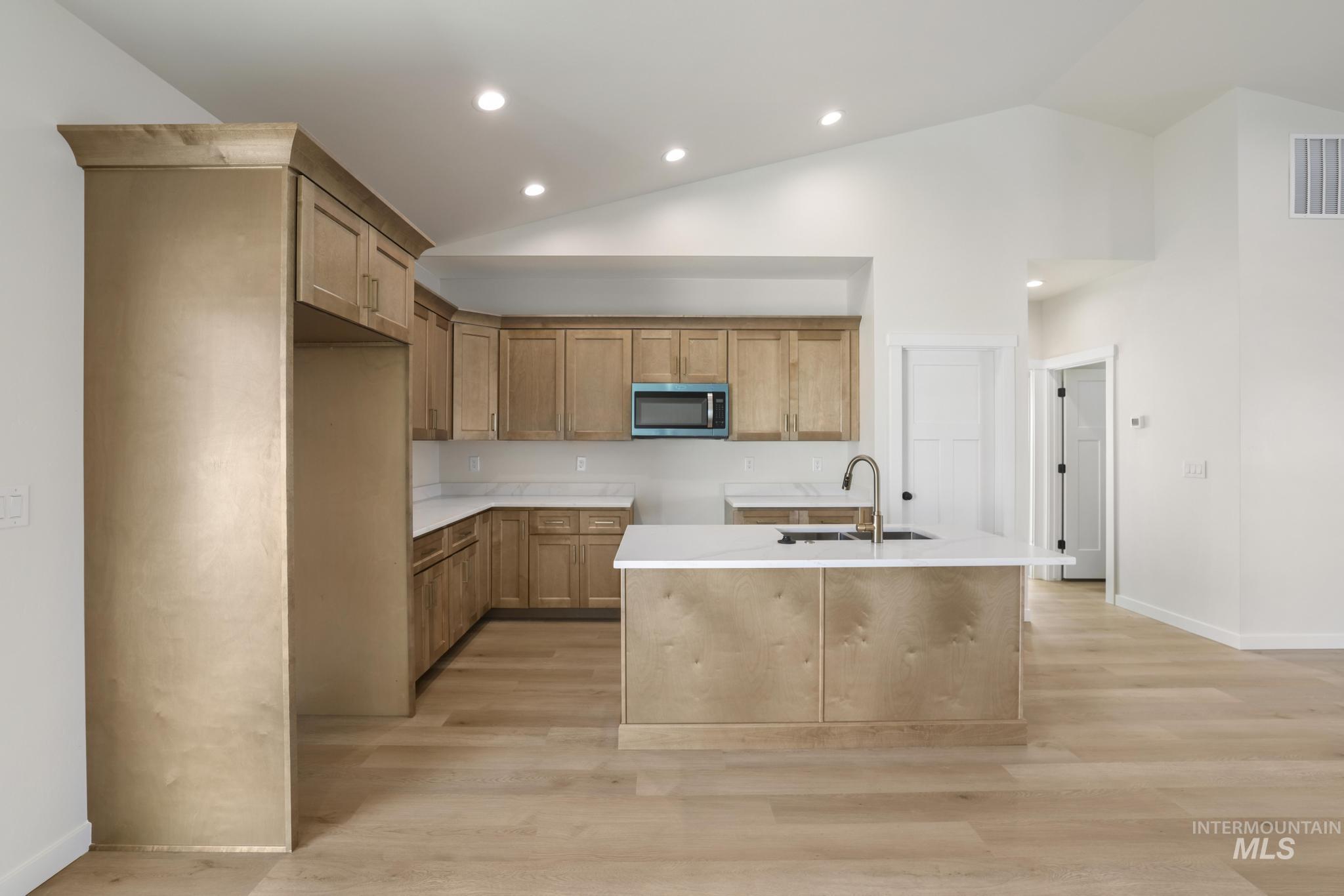 2014 Regan Street Jerome, ID 83338 - Photo 10 of 32 Kitchen featuring stainless steel microwave, a kitchen island with sink, light wood finished floors, recessed lighting, and brown cabinetry