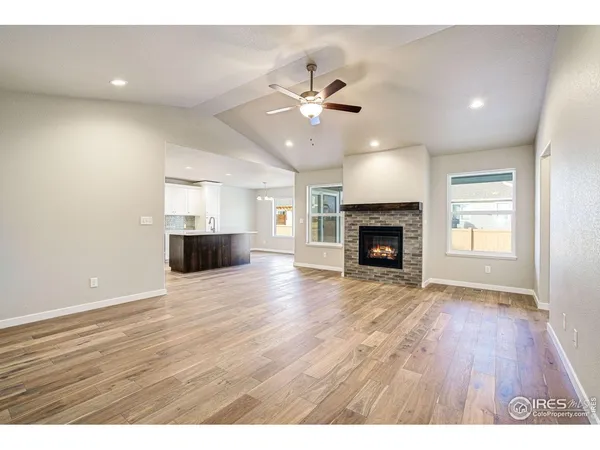 an empty room with wooden floor fireplace and fan