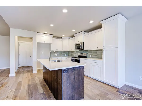 a kitchen with a sink a refrigerator and wooden floor
