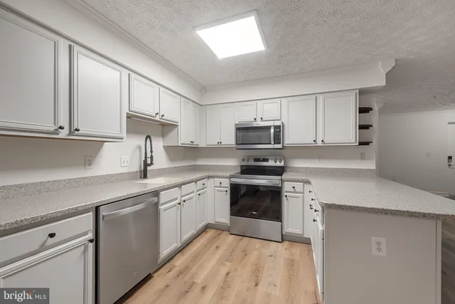 a kitchen with stainless steel appliances granite countertop a sink and dishwasher a stove top oven with white cabinets