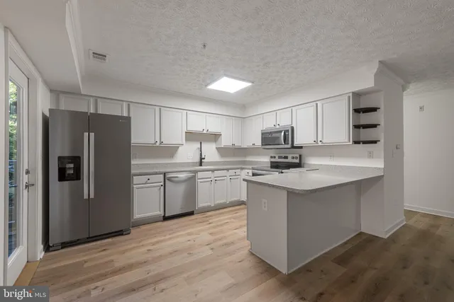 a kitchen with stainless steel appliances granite countertop a refrigerator stove a sink and dishwasher with wooden floors