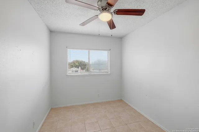an empty room with a window and a fan