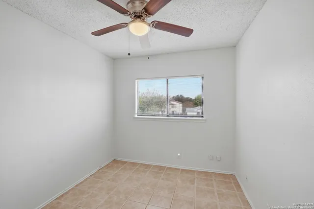 an empty room with a window and a fan