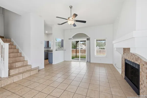 a view of a livingroom with furniture fireplace ceiling fan and windows