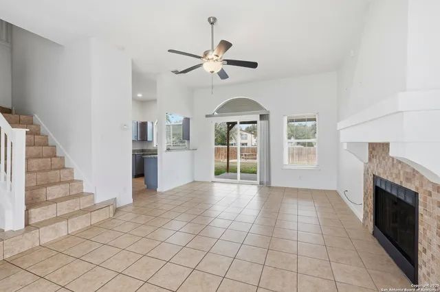 a view of a livingroom with furniture fireplace ceiling fan and windows