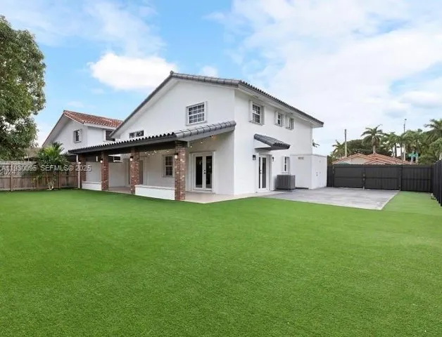 a view of a white house in front of a big yard with large trees