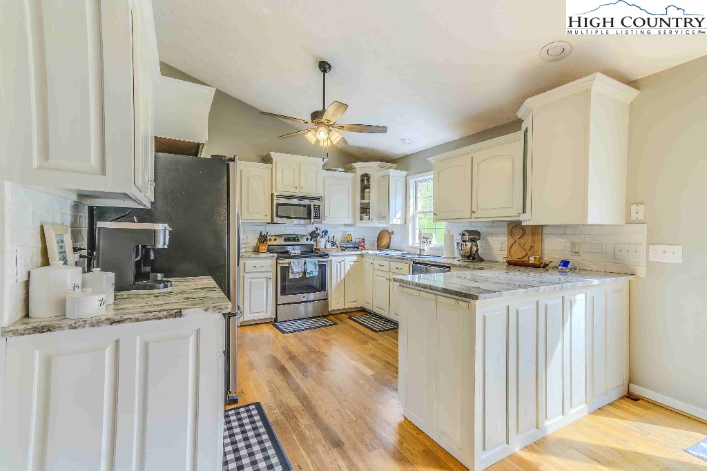 169 Violet Lane Boone, NC 28607 - Photo 13 of 27 a kitchen with kitchen island granite countertop a sink cabinets stainless steel appliances and a counter top space