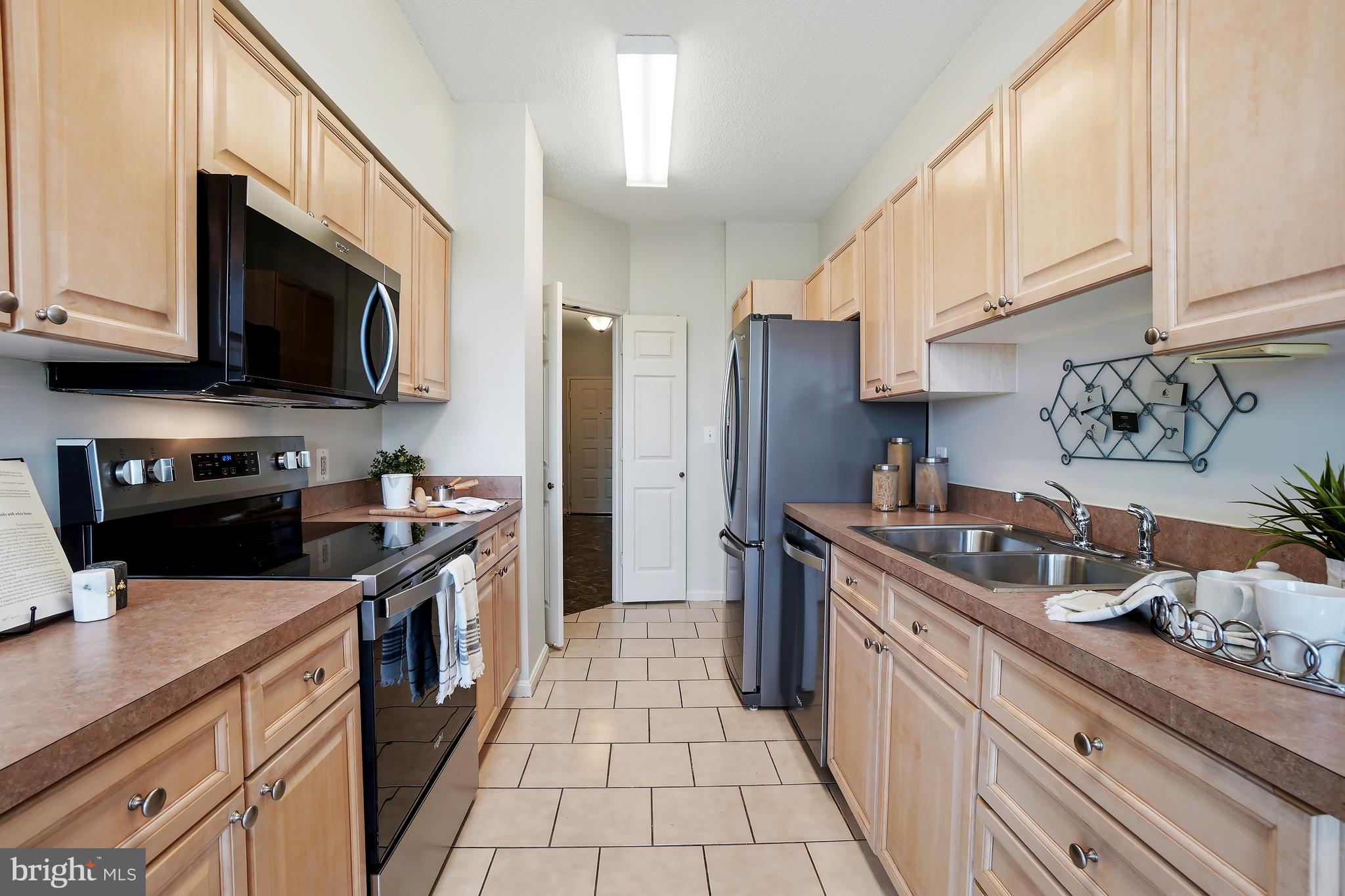 3210 North Leisure World Boulevard, Unit 1001 Silver Spring, MD 20906 - Photo 9 of 58 a kitchen with stainless steel appliances granite countertop a stove a sink and a microwave
