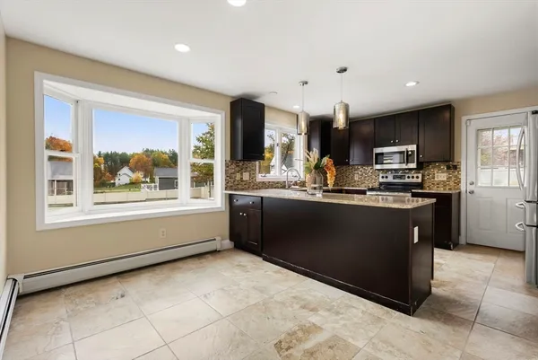 a kitchen with stainless steel appliances kitchen island granite countertop a stove a sink and a microwave