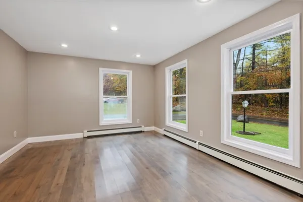 an empty room with wooden floor and windows