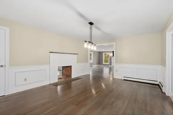an empty room with wooden floor fireplace and windows