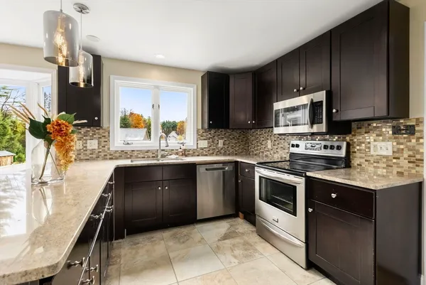 a kitchen with stainless steel appliances granite countertop wooden cabinets a stove top oven a sink and dishwasher