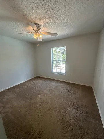 an empty room with windows and ceiling fan