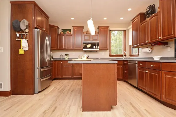 a kitchen with stainless steel appliances granite countertop a refrigerator a sink dishwasher a stove with wooden cabinets and floor