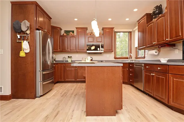 a kitchen with stainless steel appliances granite countertop a refrigerator a sink dishwasher a stove with wooden cabinets and floor