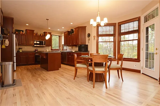 a dining room with wooden floor a chandelier a glass table and chairs