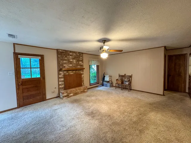 an empty room with chandelier fan and windows