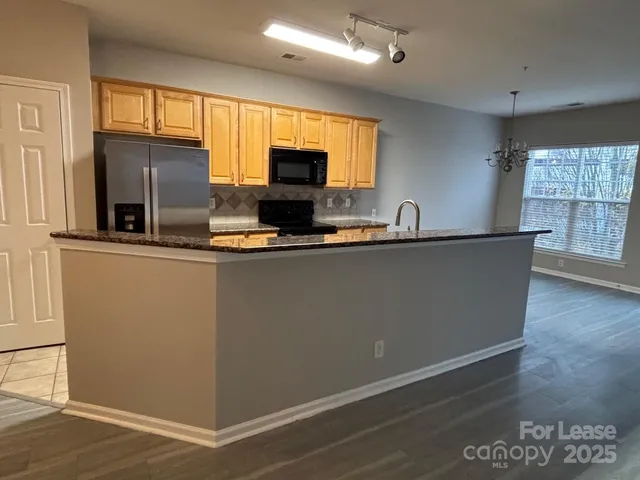 a kitchen with stainless steel appliances granite countertop a refrigerator a sink a stove a microwave a counter space and cabinets