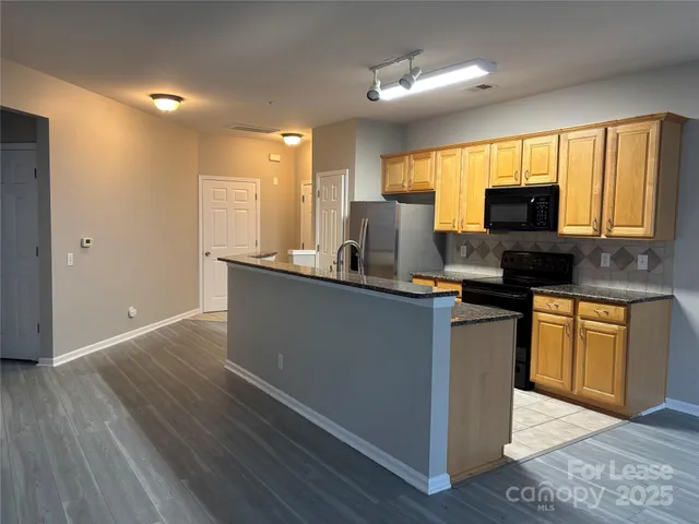 a kitchen with granite countertop a sink cabinets and wooden floor