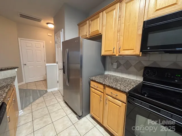 a kitchen with granite countertop a refrigerator stove and microwave