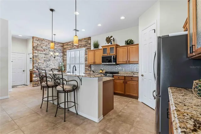 a kitchen with stainless steel appliances kitchen island granite countertop a refrigerator and a stove top oven