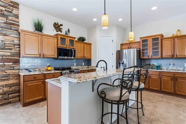 a kitchen with stainless steel appliances kitchen island granite countertop a refrigerator a stove a sink dishwasher a dining table and chairs with wooden floor