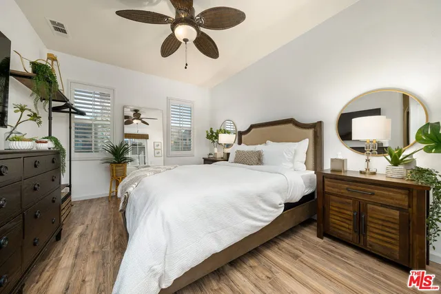 a bedroom with a bed a dresser and potted plants