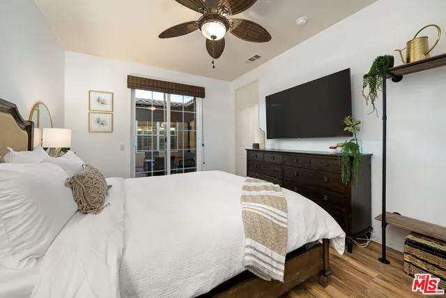a bedroom with a bed and a flat tv screen on dresser