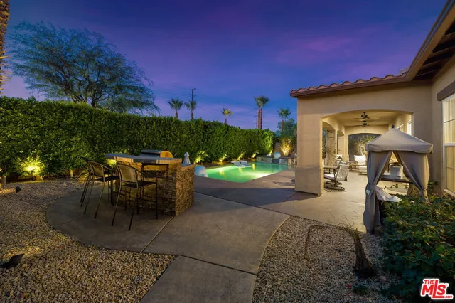 a view of a patio with table and chairs potted plants and floor to ceiling window