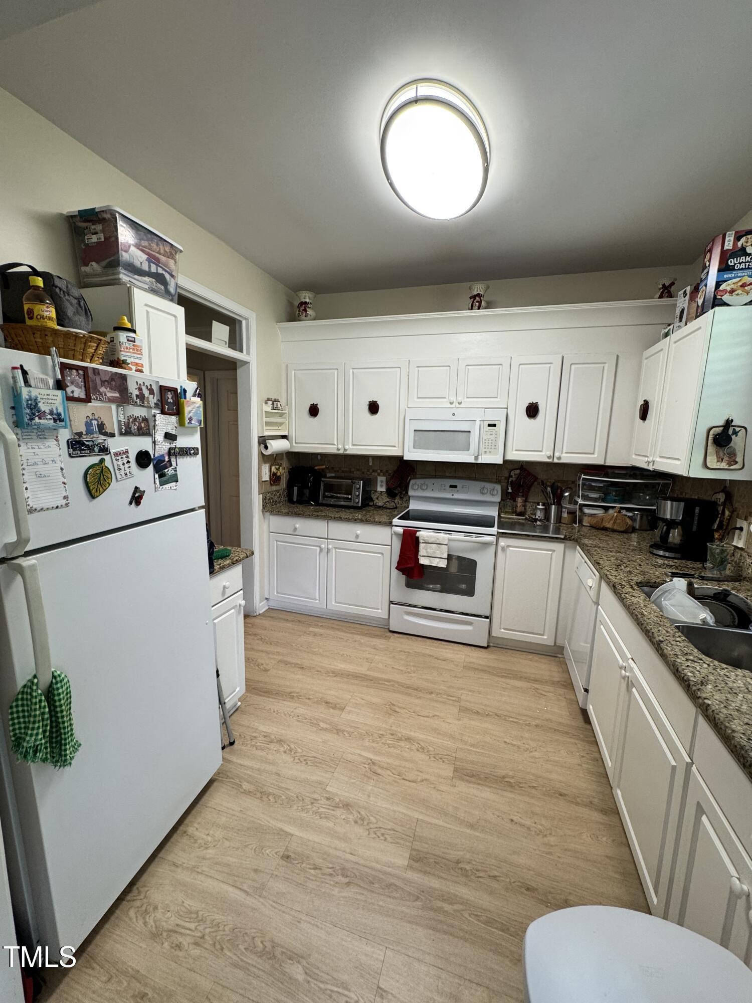 2704 Hope Diamond Court Raleigh, NC 27610 - Photo 5 of 12 a large white kitchen with stainless steel appliances granite countertop a stove a sink a refrigerator white cabinets and wooden floor