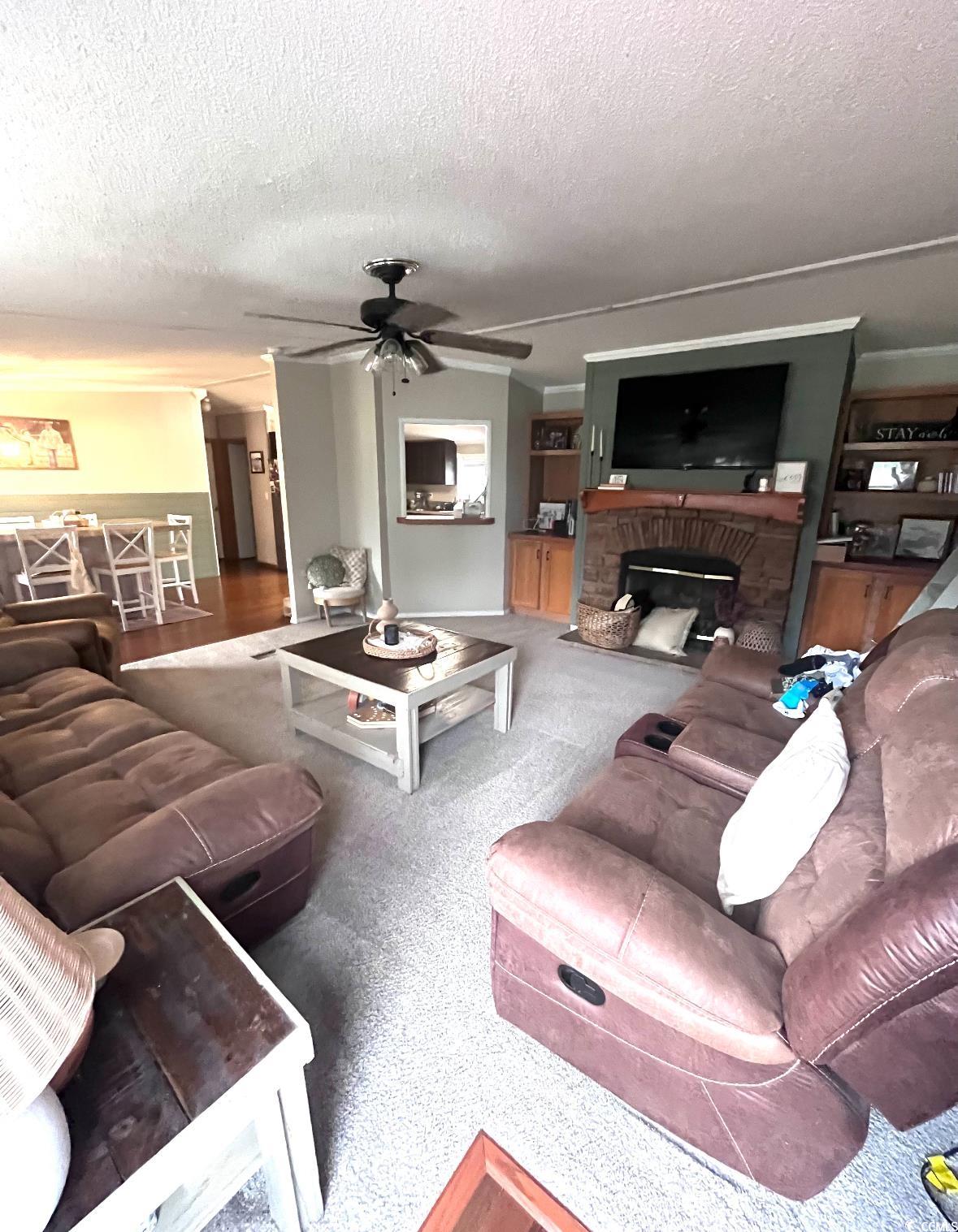7096 Johnson Shortcut Road Conway, SC 29527 - Photo 5 of 16 Living area featuring a textured ceiling, a brick fireplace, a ceiling fan, and carpet