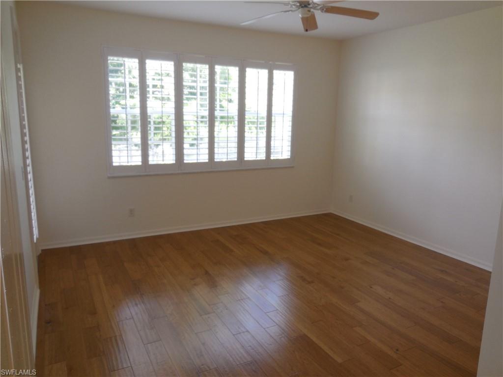 1265 Egrets Landing, Unit 101 Naples, FL 34108 - Photo 13 of 28 an empty room with wooden floor and windows