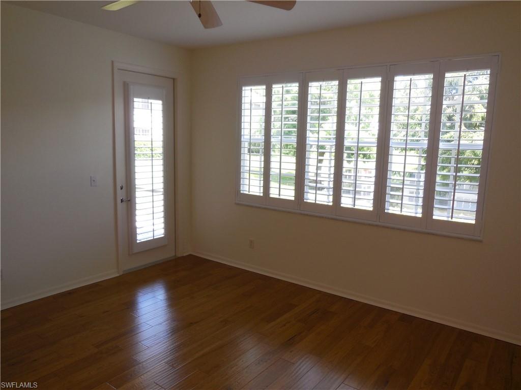 1265 Egrets Landing, Unit 101 Naples, FL 34108 - Photo 15 of 28 a view of an empty room with wooden floor and a window