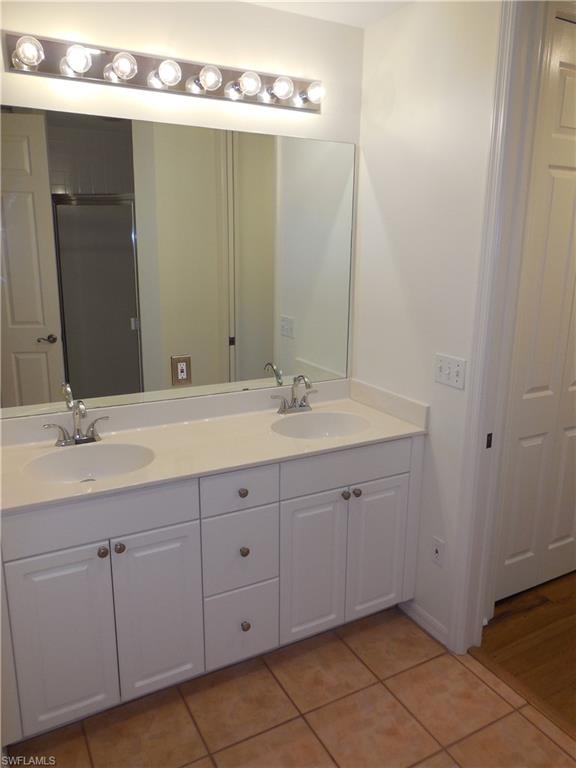 1265 Egrets Landing, Unit 101 Naples, FL 34108 - Photo 16 of 28 a bathroom with a double vanity sink and a mirror