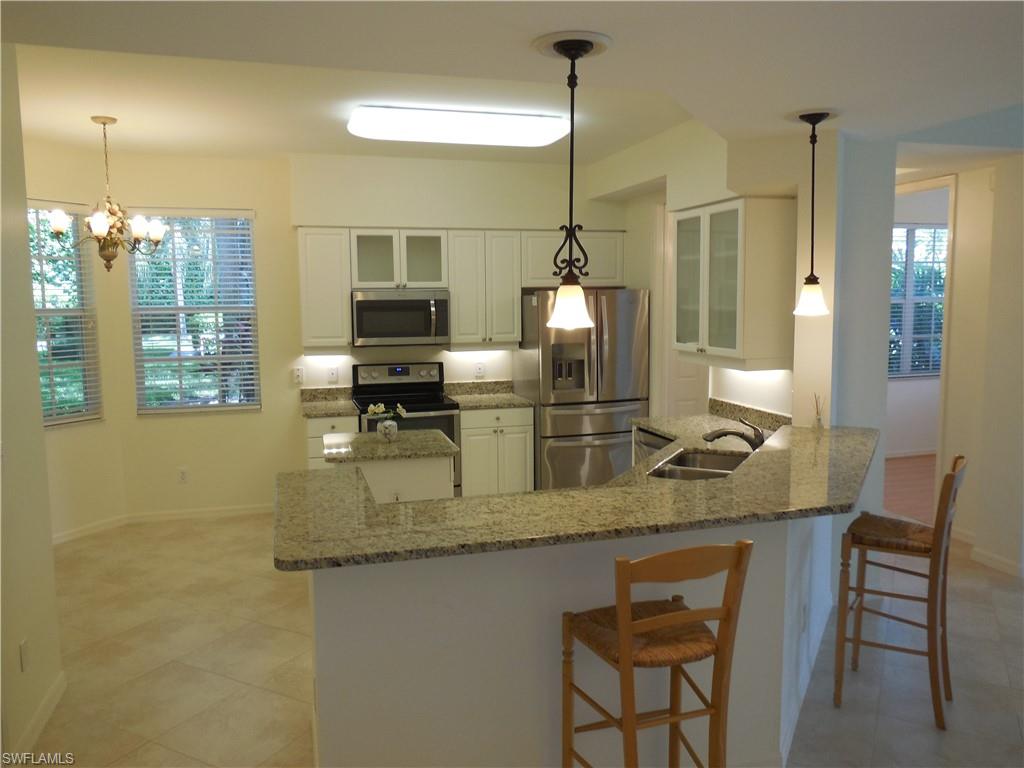 1265 Egrets Landing, Unit 101 Naples, FL 34108 - Photo 18 of 28 a kitchen with stainless steel appliances granite countertop a sink counter space and a refrigerator