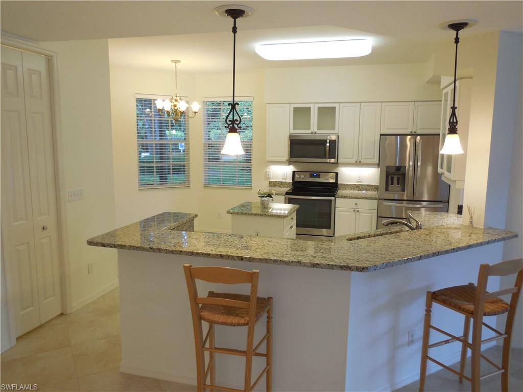 1265 Egrets Landing, Unit 101 Naples, FL 34108 - Photo 3 of 28 a kitchen with stainless steel appliances granite countertop a sink a microwave a refrigerator and microwave