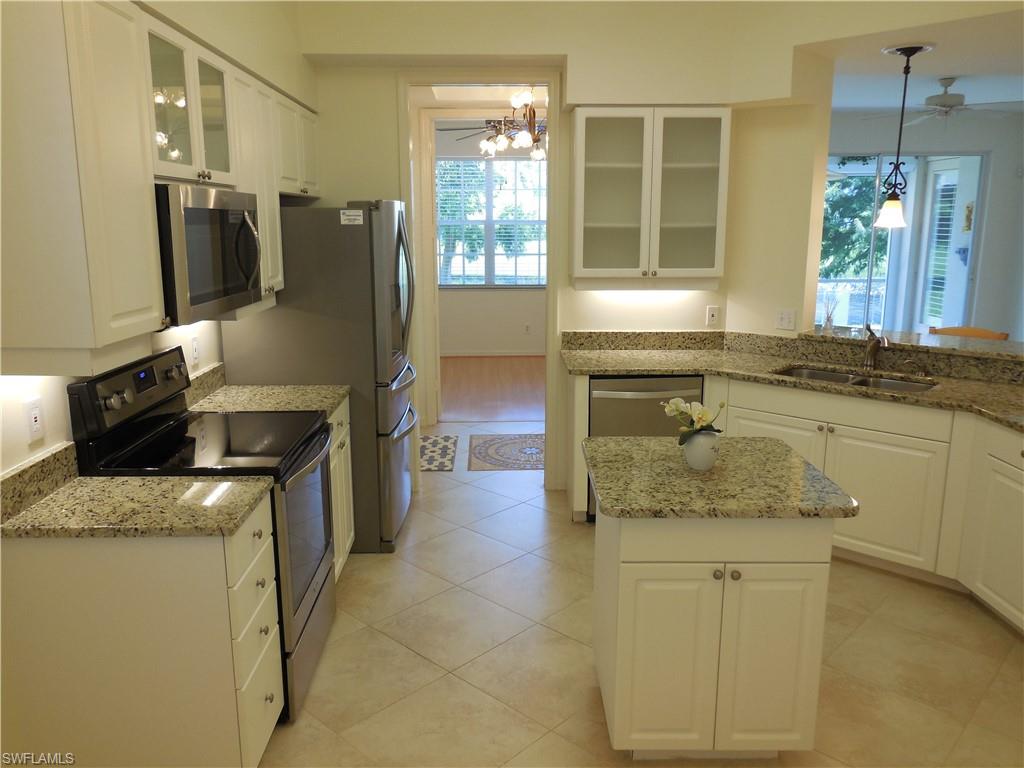 1265 Egrets Landing, Unit 101 Naples, FL 34108 - Photo 4 of 28 a kitchen with stainless steel appliances granite countertop a sink stove and refrigerator