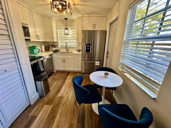 a kitchen with stainless steel appliances a refrigerator a sink a stove and white cabinets