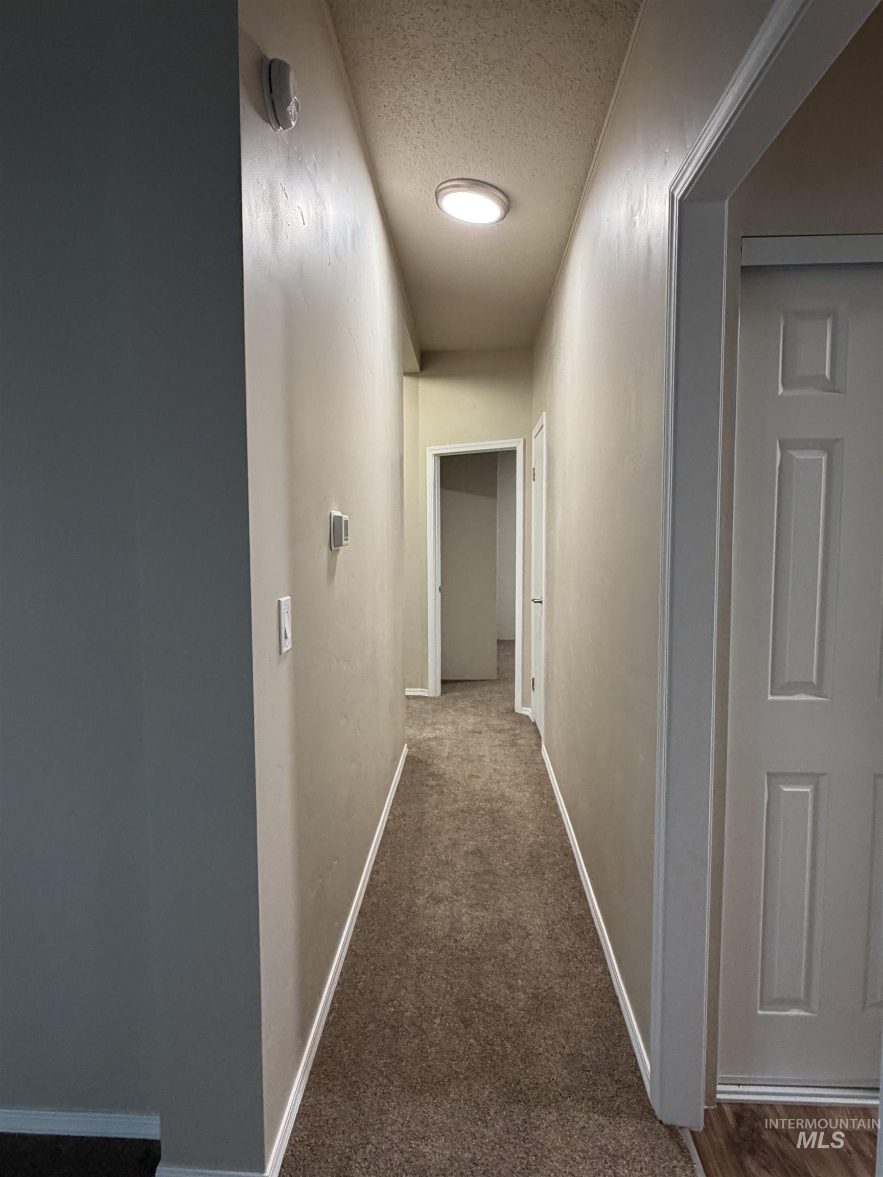 815 East Liberty Street Weiser, ID 83672 - Photo 11 of 25 Hallway featuring dark colored carpet and a textured ceiling