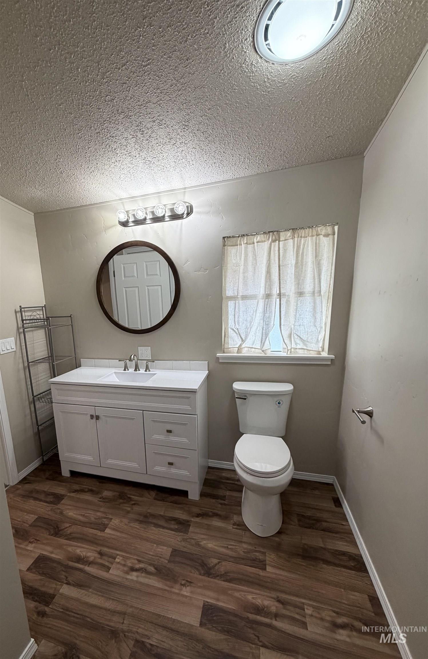 815 East Liberty Street Weiser, ID 83672 - Photo 13 of 25 Bathroom with vanity, dark wood-style flooring, and a textured ceiling