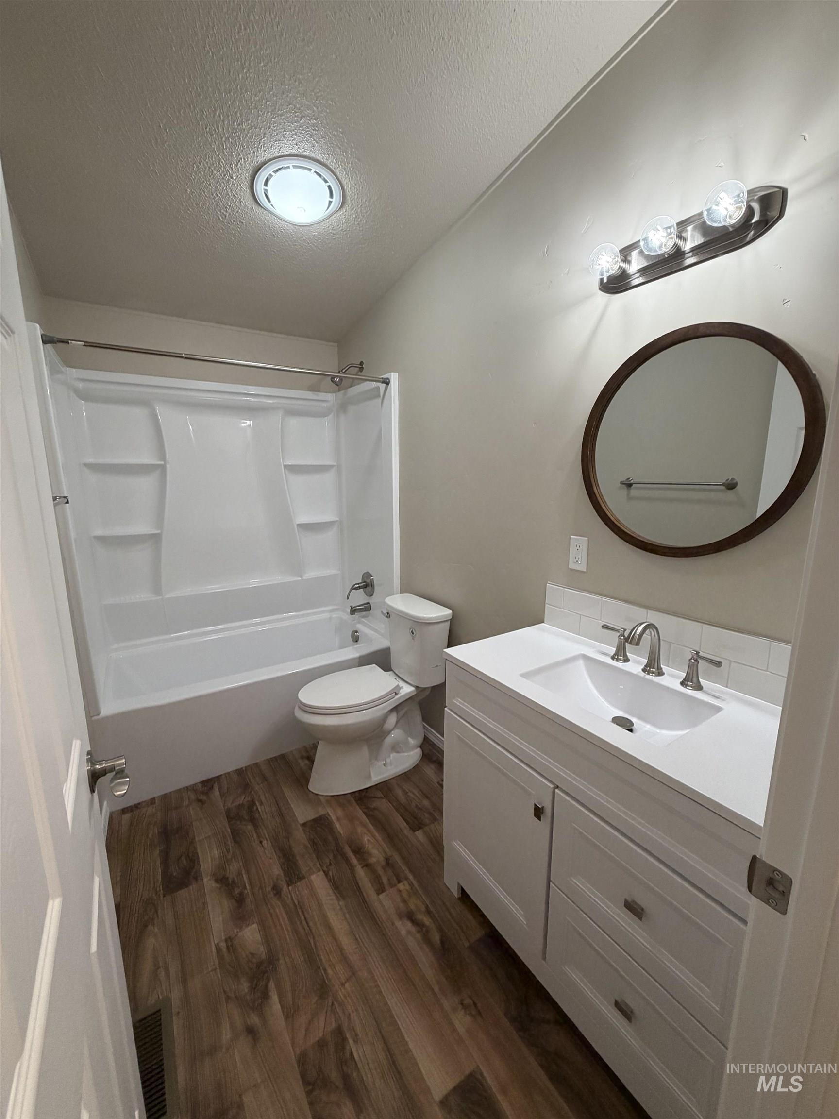 815 East Liberty Street Weiser, ID 83672 - Photo 14 of 25 Bathroom with vanity, dark wood finished floors, bathtub / shower combination, and a textured ceiling