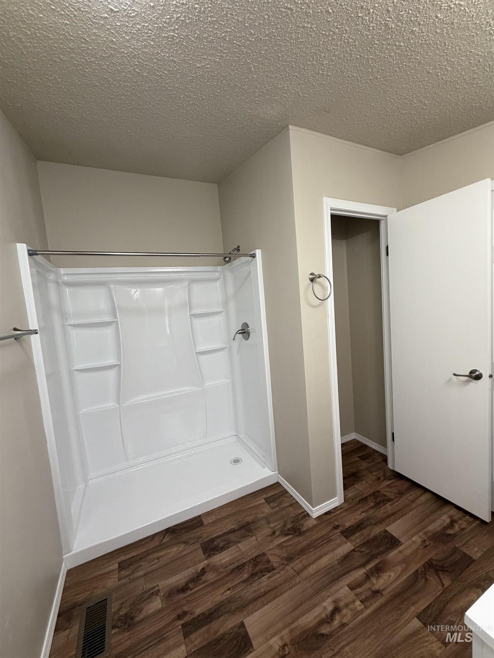 815 East Liberty Street Weiser, ID 83672 - Photo 15 of 25 Bathroom with a shower stall, a textured ceiling, and dark wood finished floors
